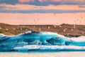 Flock of bird flying over blue iceberg floating on glacial lagoon in the evening at Jokulsarlon Royalty Free Stock Photo