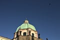 A flock of birds is flying over a dome of a baroque church Prague, Czech Republic