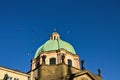 A flock of birds is flying over a dome of a baroque church Prague, Czech Republic