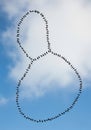 A flock of birds forms two circular patterns against a backdrop of a partly cloudy blue Royalty Free Stock Photo
