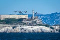 A flock of pelicans flies above Alcatraz Island. Royalty Free Stock Photo