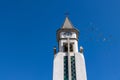 Pigeons flying around the clock tower of the chapel of Nuestra Senora de Bonanza in El Paso, La Palma, Canary Islands, Spain