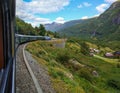 Flom, Norway - August 27, 2017: Beautiful view from the Flam railway train car to the high mountains and red wooden houses against