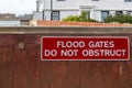 Flood gates shielding a home from flood waters with the sign reading flood gates do not obstruct