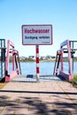 Flood high tide notice info sign on the sidewalk blocked, as a warning info board in German, German language Royalty Free Stock Photo