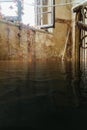 Flooded derelict staircase with sunlight coming through window