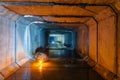 Flooded rectangular sewer tunnel with dirty urban sewage illuminated by color lights and candles