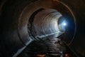 Flooded round sewer tunnel with water reflection