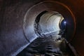 Flooded round sewer tunnel with water reflection