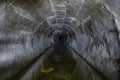 Flooded round underground drainage sewer tunnel reflecting in dirty sewage water