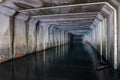 Flooded sewer tunnel is reflecting in water. Dirty urban sewage flowing throw rectangular sewer tunnel Royalty Free Stock Photo