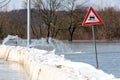 Flooded soft verge road sign next to box barriers flood protection