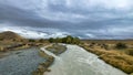 Flooded river on the winding narrow gravel road between Lake Tekapo and Lake Pukaki in rural agricultural land