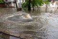 Flooding after heavy rains in city. Sewage broke open asphalt and blew up fountain. Dirty sewage broke through storm sewer and Royalty Free Stock Photo