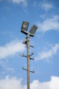 Floodlights above a football pitch with blue sky and clouds in the background