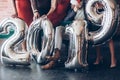 On the floor. Group of friends with inflatable numbers in hands celebrating new 2019 year Royalty Free Stock Photo
