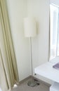 A floor lamp in the corner of the hotel room. A mirror and a console with a notebook. Royalty Free Stock Photo