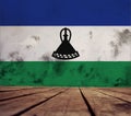 The floor of planks and plastered wall with the Kingdom of Lesotho flag.