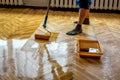 Floor renovation. Worker lacquering parquet floors using roller