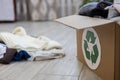 On the floor in the room there is a box with folded clothes and a recycling sign. Next to the box is a pile of clothes Royalty Free Stock Photo