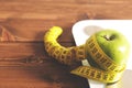 Floor scales, tape measure and green apple on a wood background top view. The concept of a healthy diet, body weight Royalty Free Stock Photo