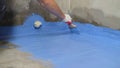A worker is applying waterproofing paint to the floor in the bathroom. Floor waterproofing in blue. Royalty Free Stock Photo