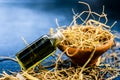 Close up of floral and herbal essence of khus or vetiver grass in a small glass bottle along with raw dried khus on wooden surface