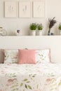 Floral bedding and pastel pink cushion on double bed in real photo of white bedroom interior with lavender, posters and decor Royalty Free Stock Photo