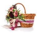 Floral Composition With Flowers, Greenery And Ribbons Hanging On The Handle Of A Wicker Basket On White Background