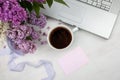 Floral composition made of beautiful purple lilac on white wooden background with cup of coffee. Feminine office desk Royalty Free Stock Photo