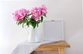 Floral composition, vase with peonies on an old wooden bench. White wall background. Scandinavian interior room design