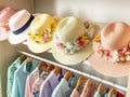 Floral-decorated straw hats above a rack of pastel dresses.