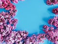 Floral frame of fresh lilac flowers on blue background. Top view, copy space, flower flatlay. Place for text or beauty product Royalty Free Stock Photo