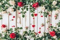 Floral frame made of red roses, green leaves and hearts on white wooden background Royalty Free Stock Photo