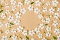 Floral frame made of white spring flowers, buds and green leaves on brown paper background. Flat lay. Royalty Free Stock Photo