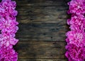 Floral frame with pink peonies flowers on wood background. Selective focus, place for text, top view