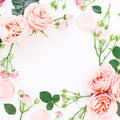 Floral frame of pink roses, buds and leaves on white background. Flat lay, top view. Floral background.