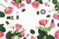 Floral frame with pink roses flowers and feminine cosmetics on white background. Flat lay, top view. Royalty Free Stock Photo