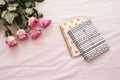 Floral frame with stunning pink roses and notebooks on pink bed sheets in the bedroom. Freelance workspace. Wedding, gift card, va Royalty Free Stock Photo