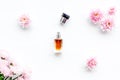 Floral perfume for women. Bottle of perfume near delicate pink flowers on white background top view pattern
