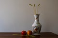 Floral pottery vase with ears of wheat and apples on wooden table in a still life photo Royalty Free Stock Photo