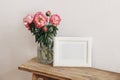 Floral still life scene. Pink peonies flowers, bouquet in glass vase on wooden table. White horizontal picture frame