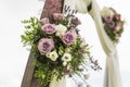 Floral wooden arch with white cloth and fresh violet pink white flowers with green leaves on a rustic wedding ceremony.