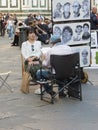 Asian tourist posing in front of a street cartoonist in Florence