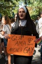 Portrait of an unidentified participant dressed as a nun, holds a sign that reads JESUS LOVES GAYS AS WELL, during the