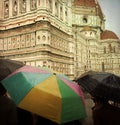 Tourists shelter beneath colorful umbrellas