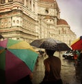 Tourists shelter beneath colorful umbrellas