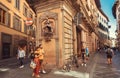Tourists walking under historical reliefs of narrow streets houses of ancient Tuscany city