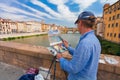 Florence, ITALY- September 10, 2016: Painter paints the picture of city scenery of medieval stone bridge Ponte Vecchio and the Arn