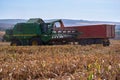 Floresti, Moldova. September 11, 2019: Green combine harvester machine unloading sorghum into a red trailer truck Royalty Free Stock Photo